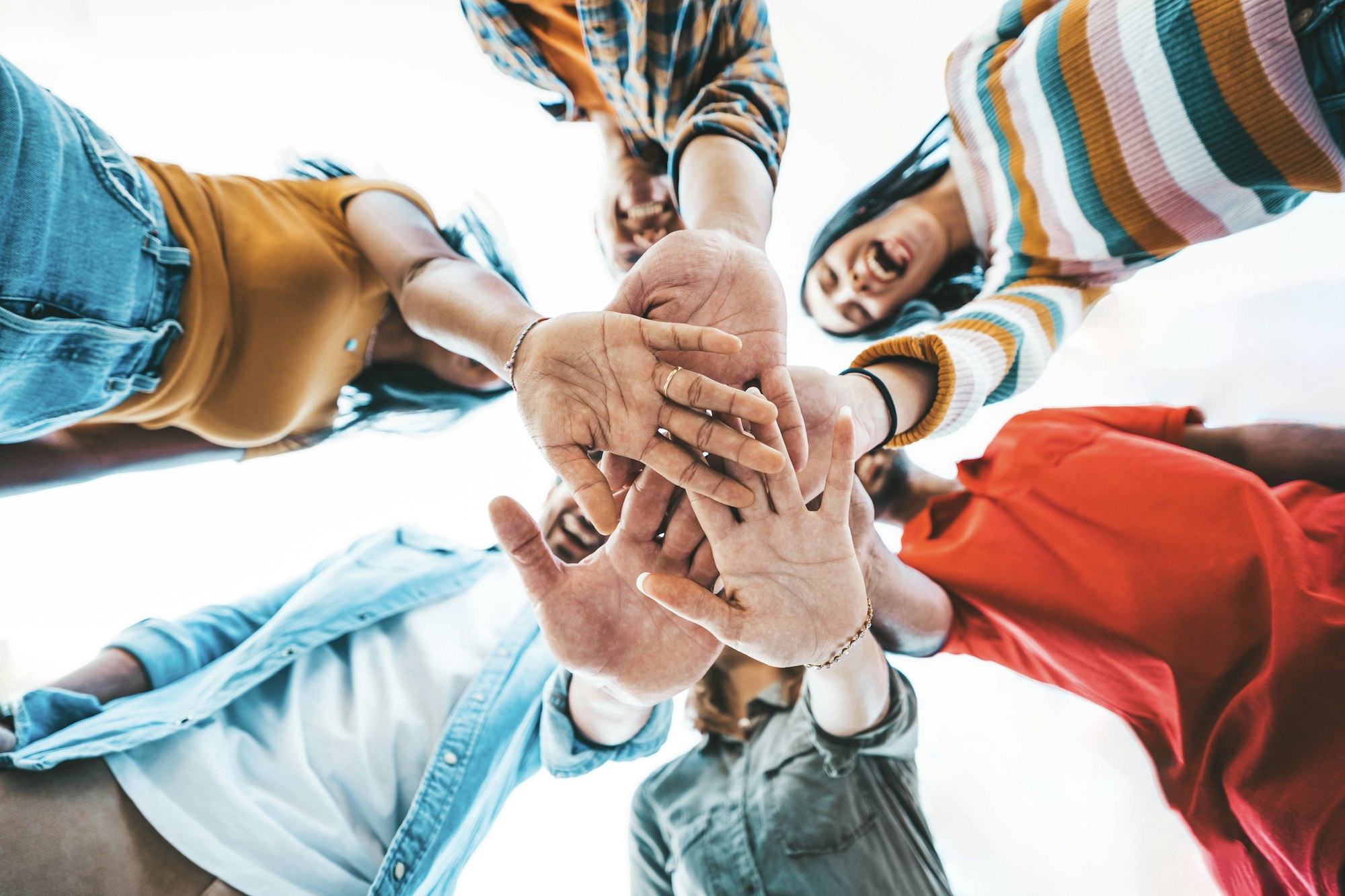 Community of millennial people stacking hands together